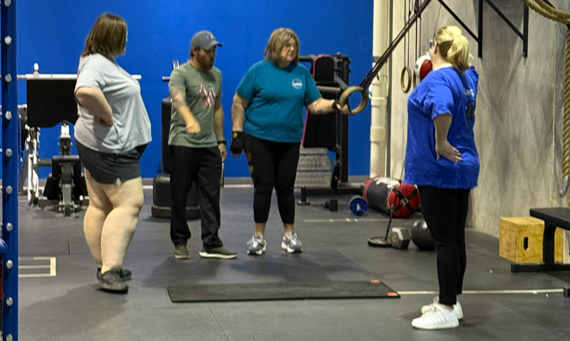Small group fitness class with trainer demonstrating exercise at Freedom Fitness gym in St. Peters, Missouri