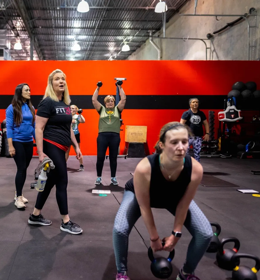 Woman performing barbell deadlift with trainer coaching at Freedom Fitness gym in St. Peters, Missouri