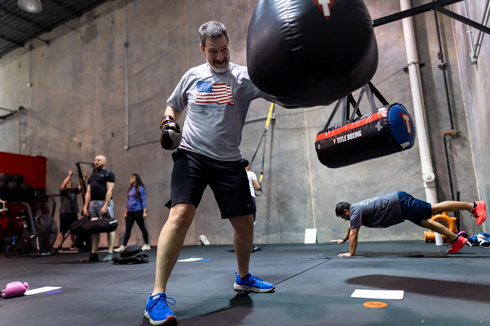 Man hitting heavy bag while others train in group fitness class at Freedom Fitness gym in St. Peters, Missouri