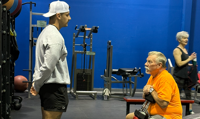 Senior man lifting dumbbells with trainer guidance at Freedom Fitness gym in St. Peters, Missouri