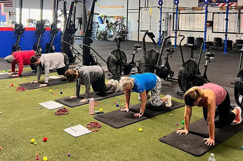 Group fitness class doing mobility and core exercises on mats at Freedom Fitness gym in St. Peters, Missouri