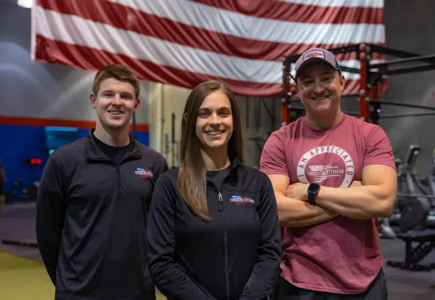 Freedom Fitness trainers posing together in gym with American flag in St. Peters, Missouri